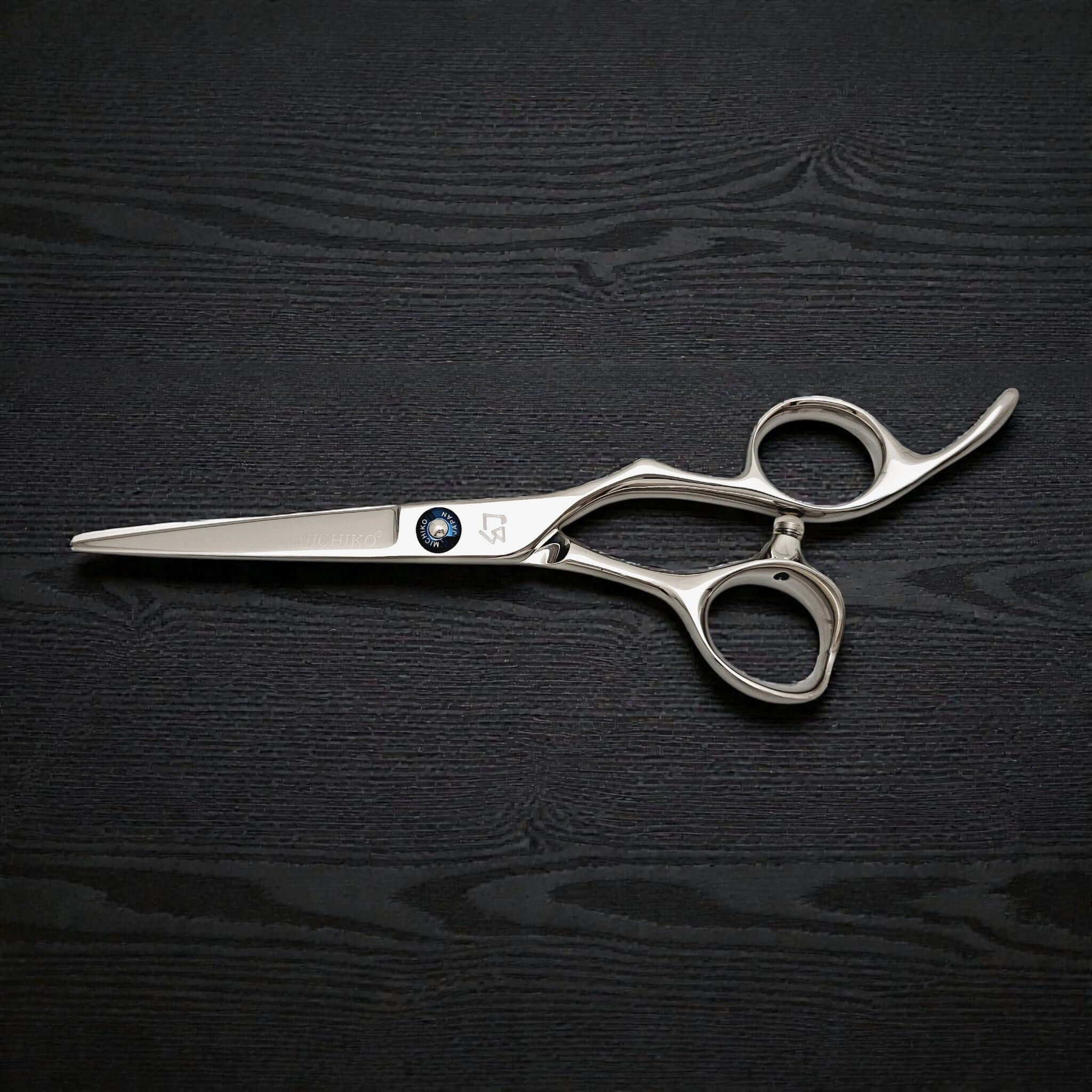 Silver scissors on a black wooden surface