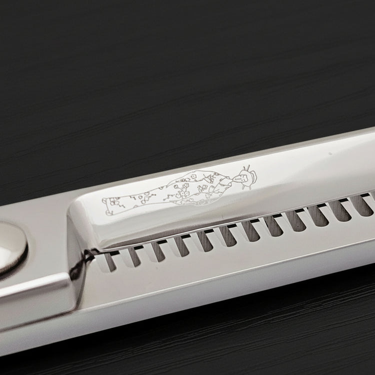 Close-up of the back of hair-thinning scissors blades with an engraved Japanese lady logo on a black background