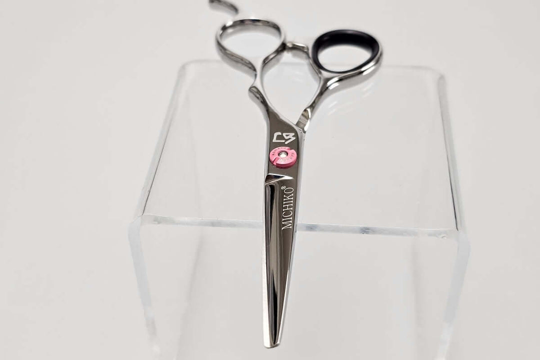 Hair scissors with a pink screw on a white background