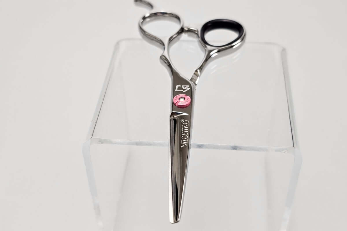 Hair scissors with a pink screw on a white background
