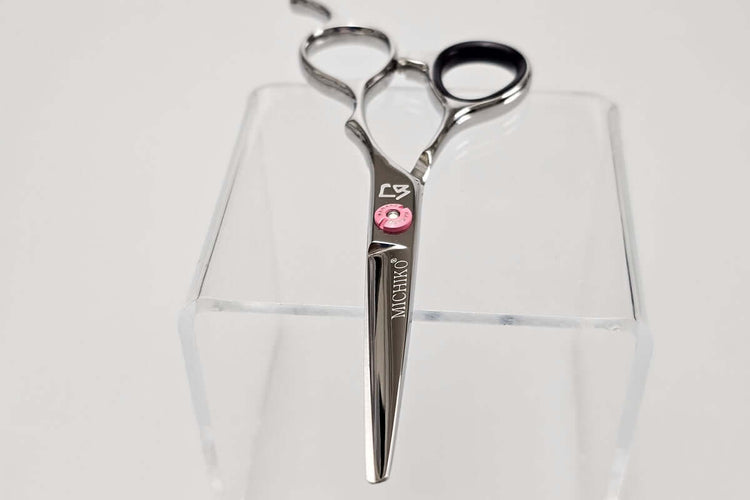 Hair scissors with a pink screw on a white background