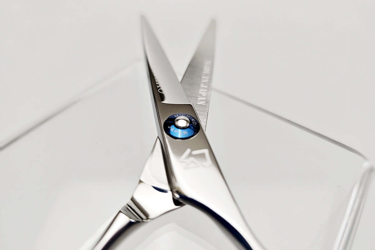 Close-up of a pair of hair scissors with a MICHIKO brand name on a white background