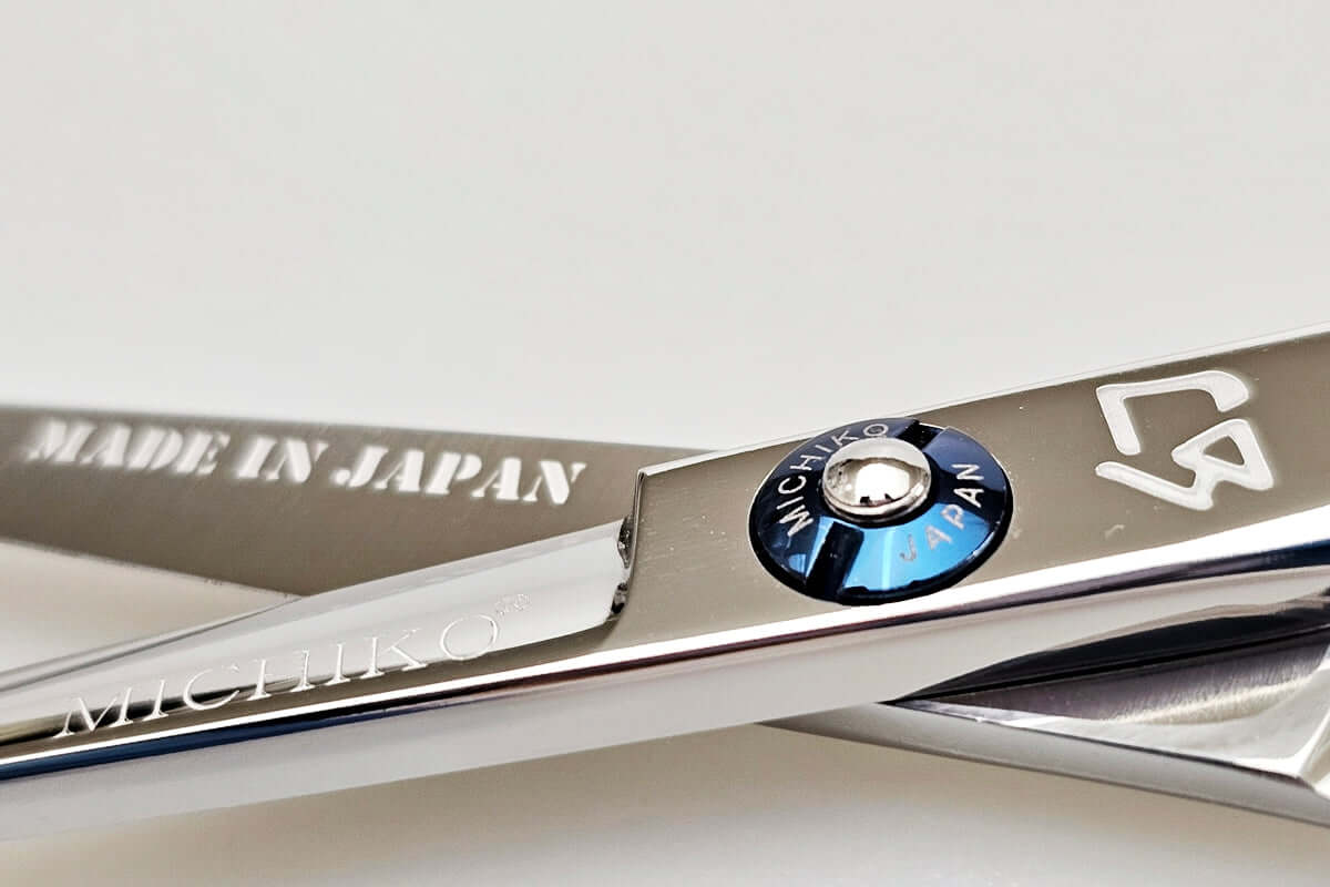 Close-up of a pair of hair scissors with 'Made in Japan' and 'Michihiro' branding on a light background.