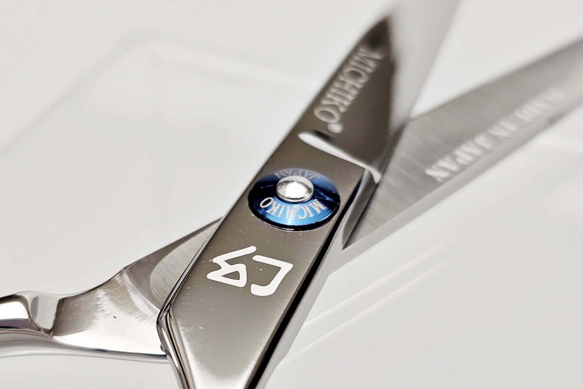 Close-up of a pair of hair scissors with a MICHIKO brand logo on a white background