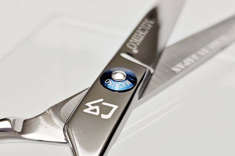 Close-up of a pair of hair scissors with a MICHIKO brand logo on a white background