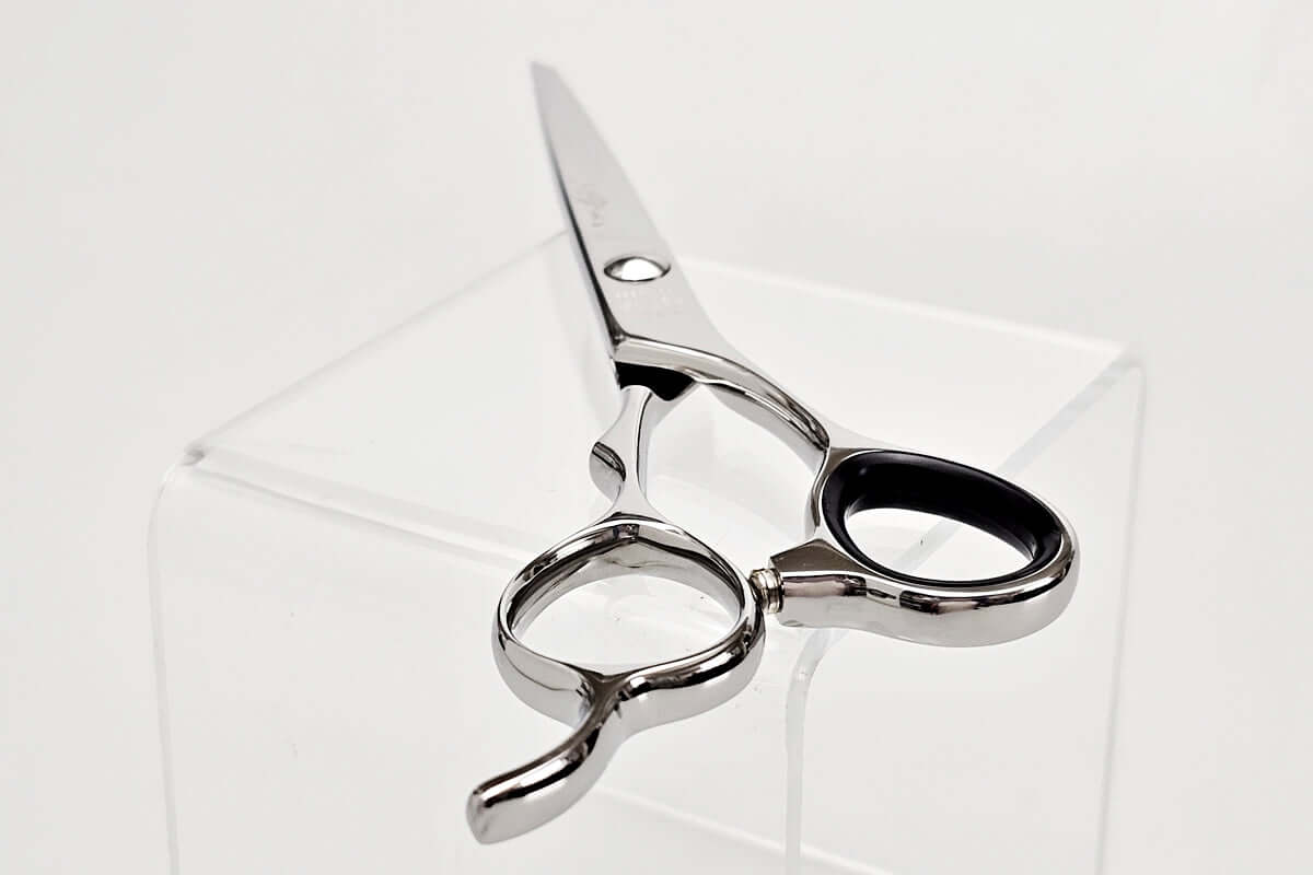 Hair scissors on a clear stand against a white background