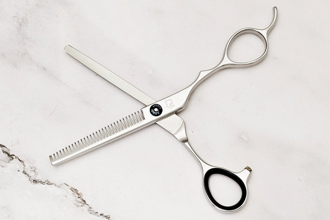 Pair of hair thinning scissors on a marble surface