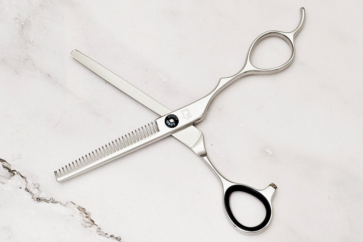 Pair of hair thinning scissors on a marble surface