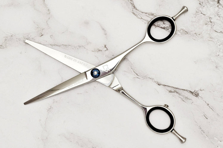 Pair of hair scissors on a marble surface