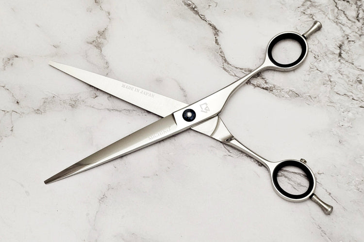 Hair cutting scissors on a white marble background.
