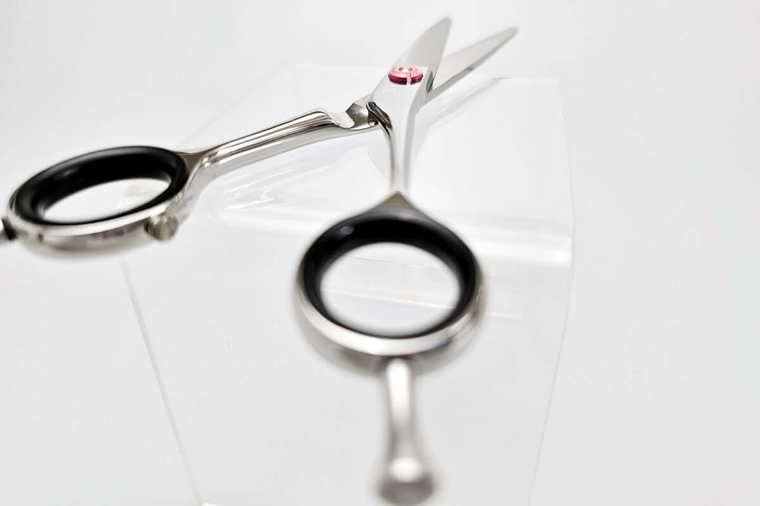 Pair of black-handled hair scissors on a white background