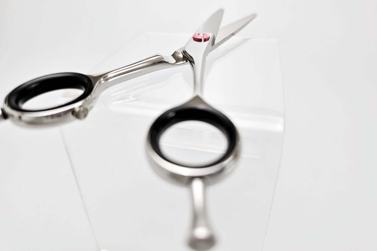 Pair of black-handled hair scissors on a white background