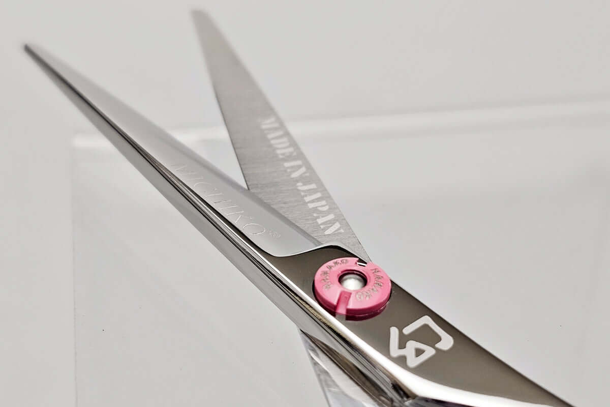 Close-up of a pair of hair scissors with the MICHIKO brand logo on a light gray background