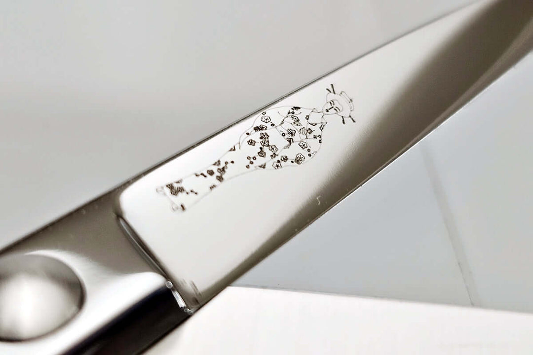 Close-up of hair scissor blade with the engraved MICHIKO lady logo on a white background