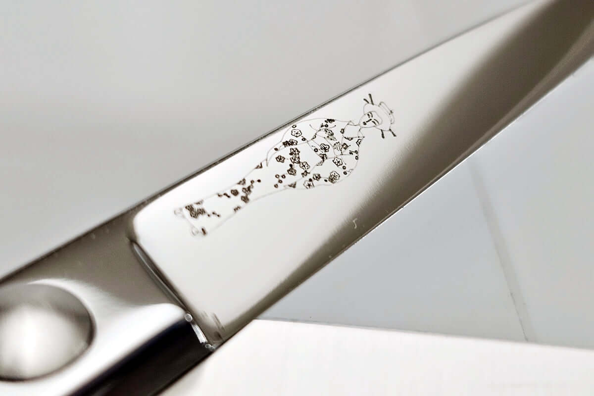 Close-up of hair scissor blade with the engraved MICHIKO lady logo on a white background