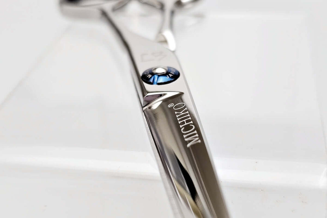 Close-up of a hair cutting scissors with 'Michiko' branding on a light background