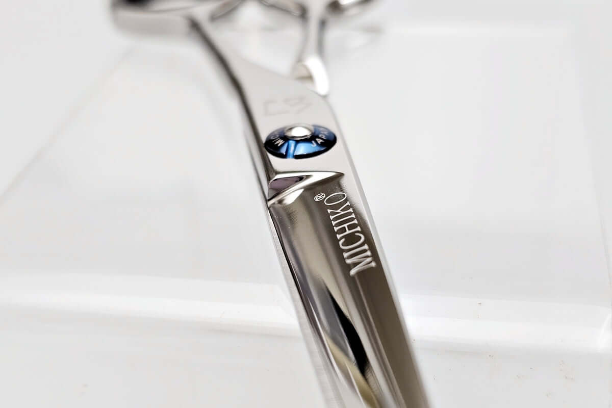 Close-up of a hair cutting scissors with 'Michiko' branding on a light background