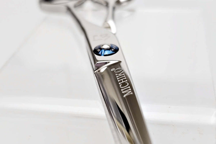 Close-up of a hair cutting scissors with 'Michiko' branding on a light background