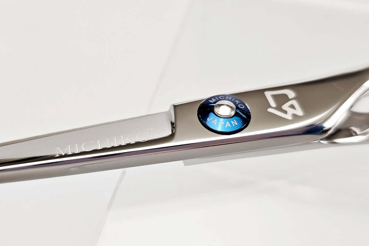 Close-up of a silver hair cutting scissors with brand logos on a white background