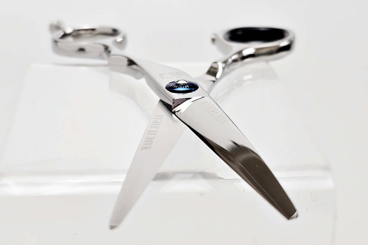 Silver hair scissors with a blue screw design on a white background
