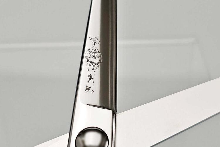 Close-up of hair scissor blade with a MICHIKO lady logo on a gray background