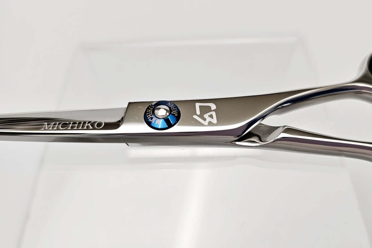 Close-up of a pair of hair scissors with visible branding on a light gray background