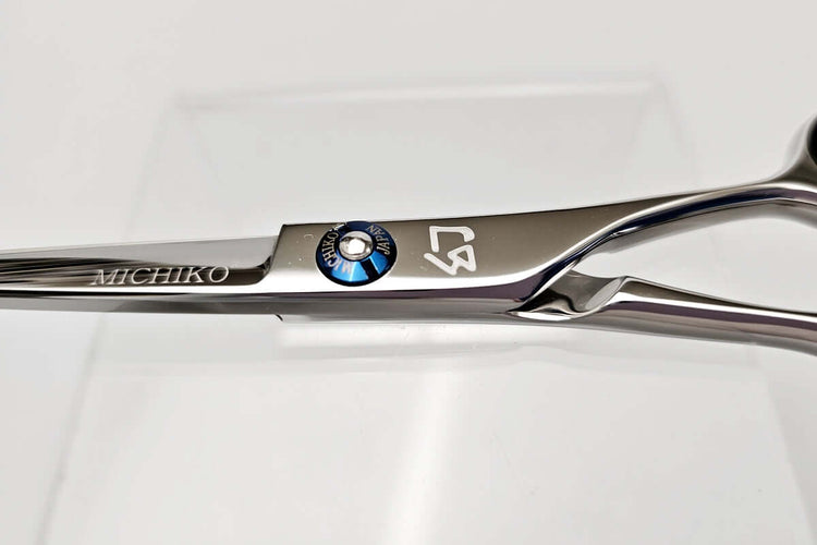 Close-up of a pair of hair scissors with visible branding on a light gray background