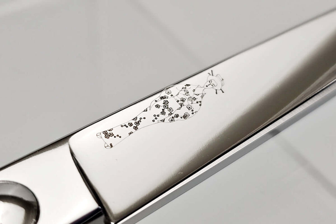 Close-up of a hair scissors blade with the MICHIKO lady logo engraved on a light gray background