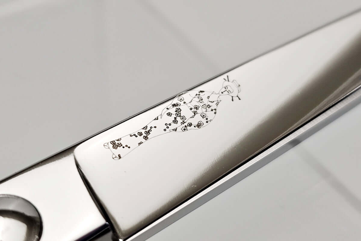 Close-up of a hair scissors blade with the MICHIKO lady logo engraved on a light gray background