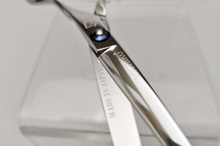 Close-up of a pair of scissors with a brand name on a light gray background