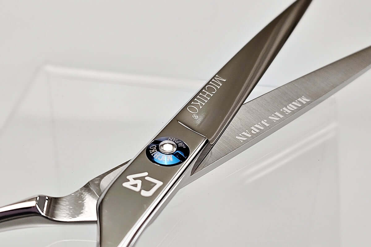 Close-up of a pair of hair scissors with MICHIKO brand names on a white background
