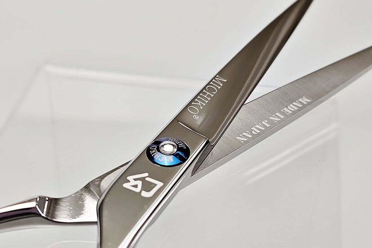 Close-up of a pair of hair scissors with MICHIKO brand names on a white background