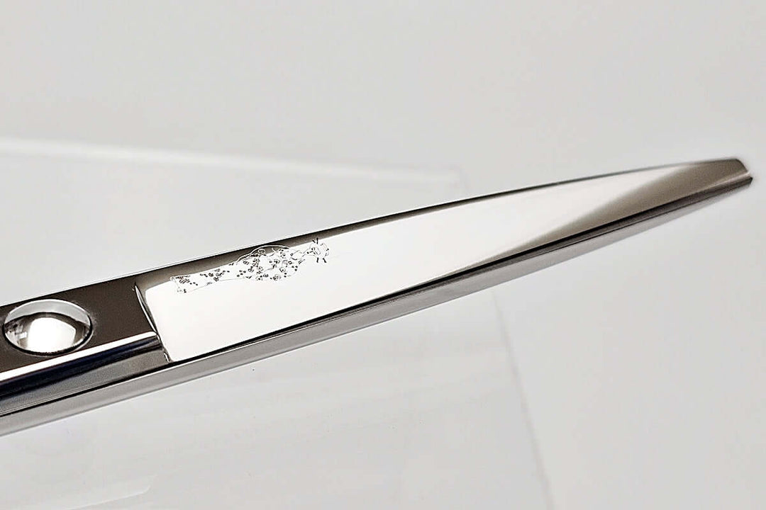 Close-up of hair scissors blade with the MICHIKO lady logo on a light gray background