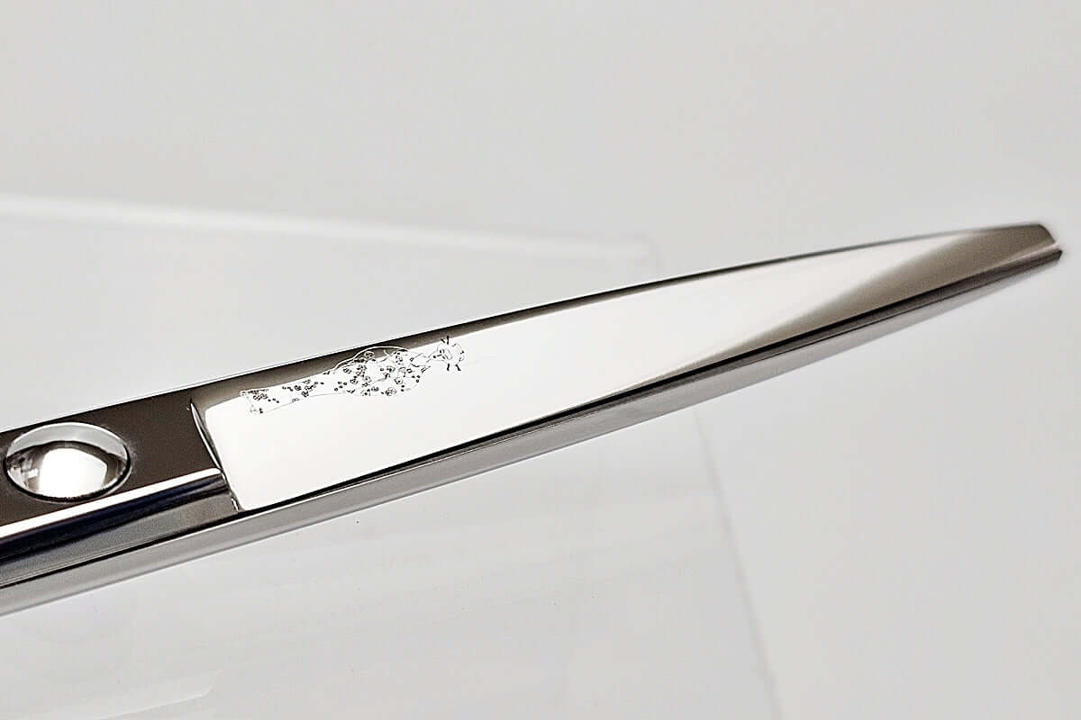 Close-up of hair scissors blade with the MICHIKO lady logo on a light gray background