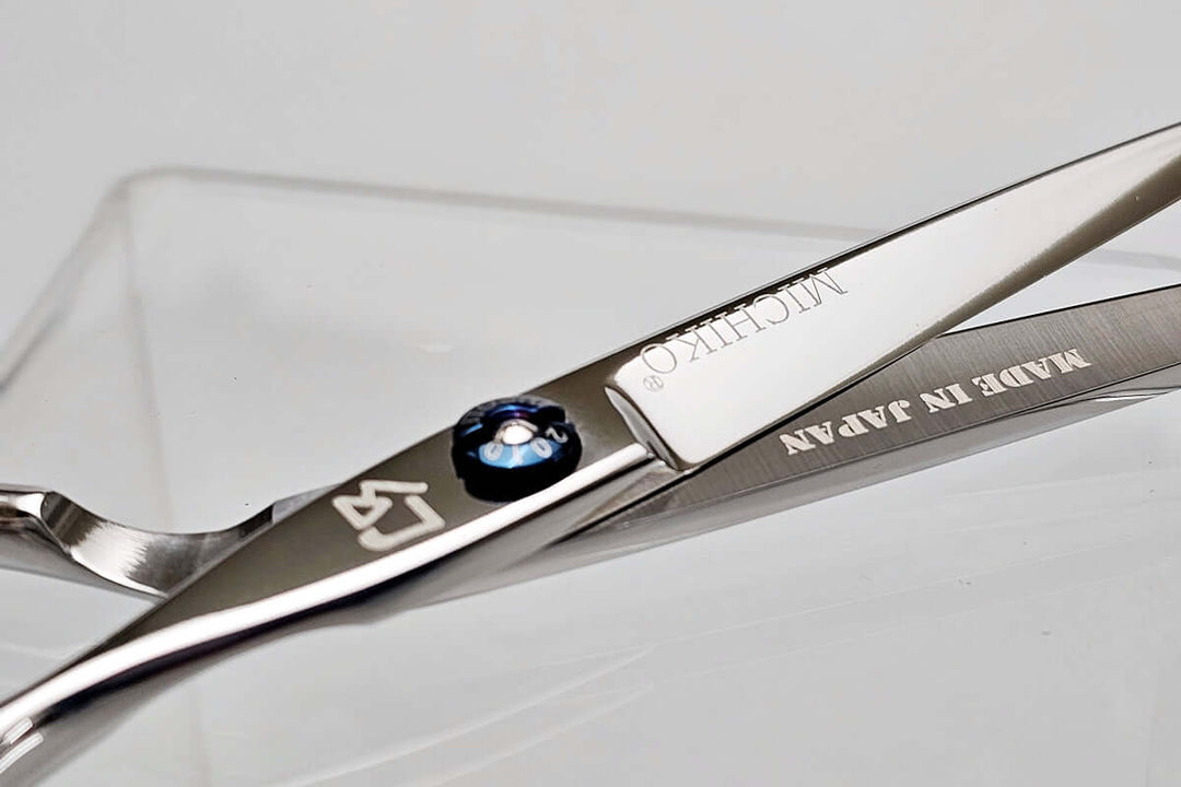 Close-up of a pair of hair scissors with 'Michiko' branding on a light gray background