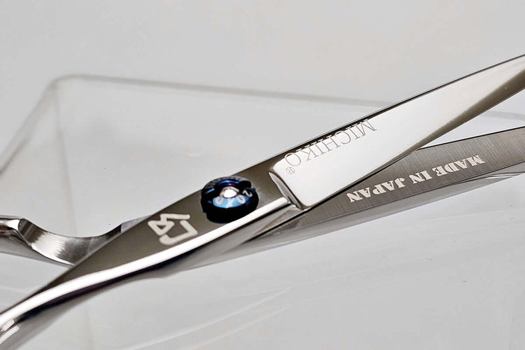 Close-up of a pair of hair scissors with 'Michiko' branding on a light gray background