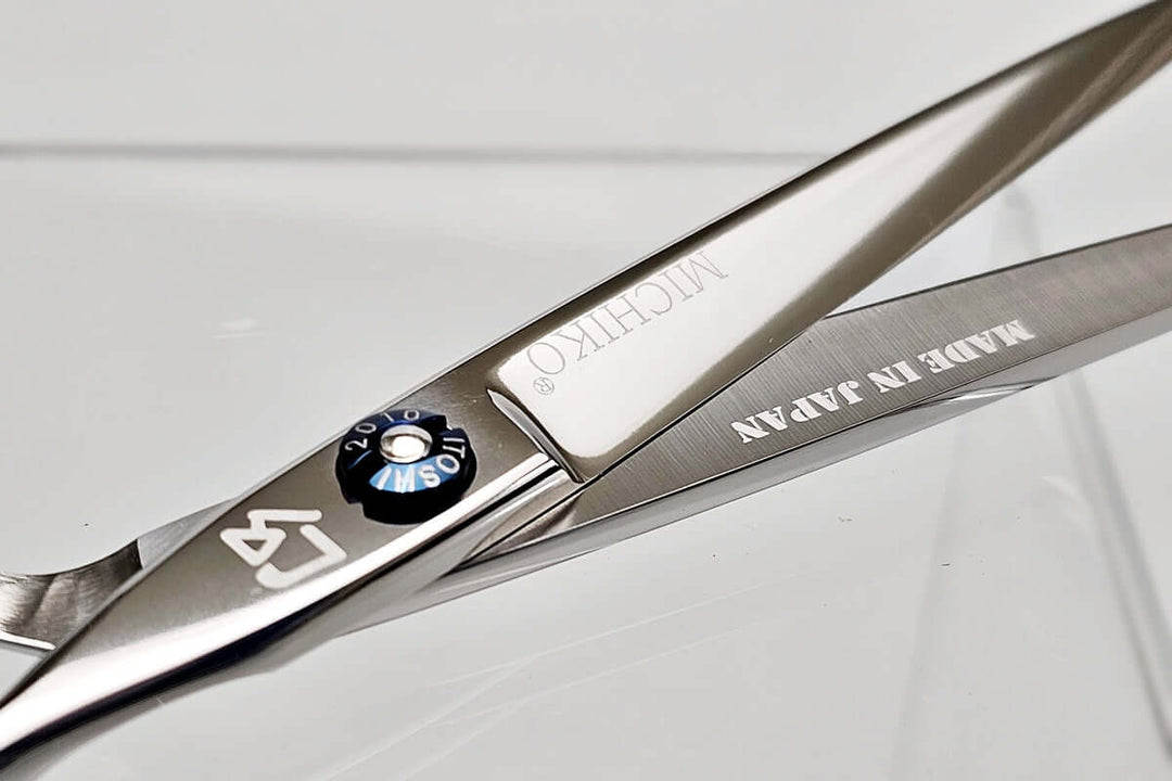 Close-up of a pair of hair scissors with 'Michiko' branding on a light gray background