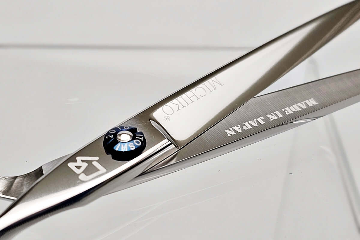 Close-up of a pair of hair scissors with 'Michiko' branding on a light gray background