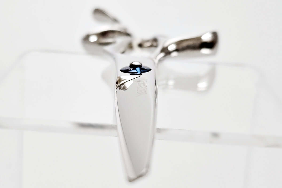 Hair scissors with a blue screw on a light gray background