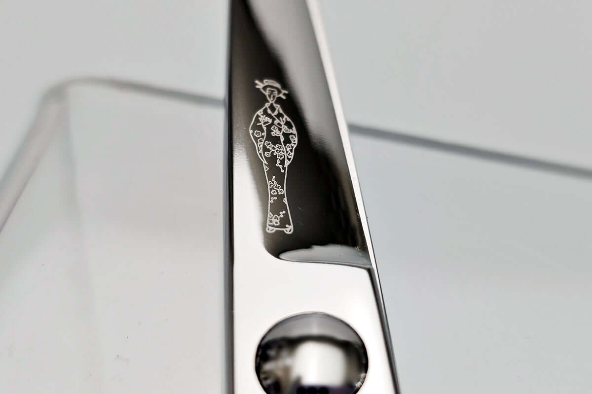Close-up of hair scissors blade with the MICHIKO lady logo on a gray background