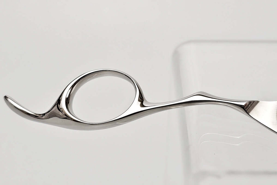 Close-up of a hair scissors finger ring on a light gray background