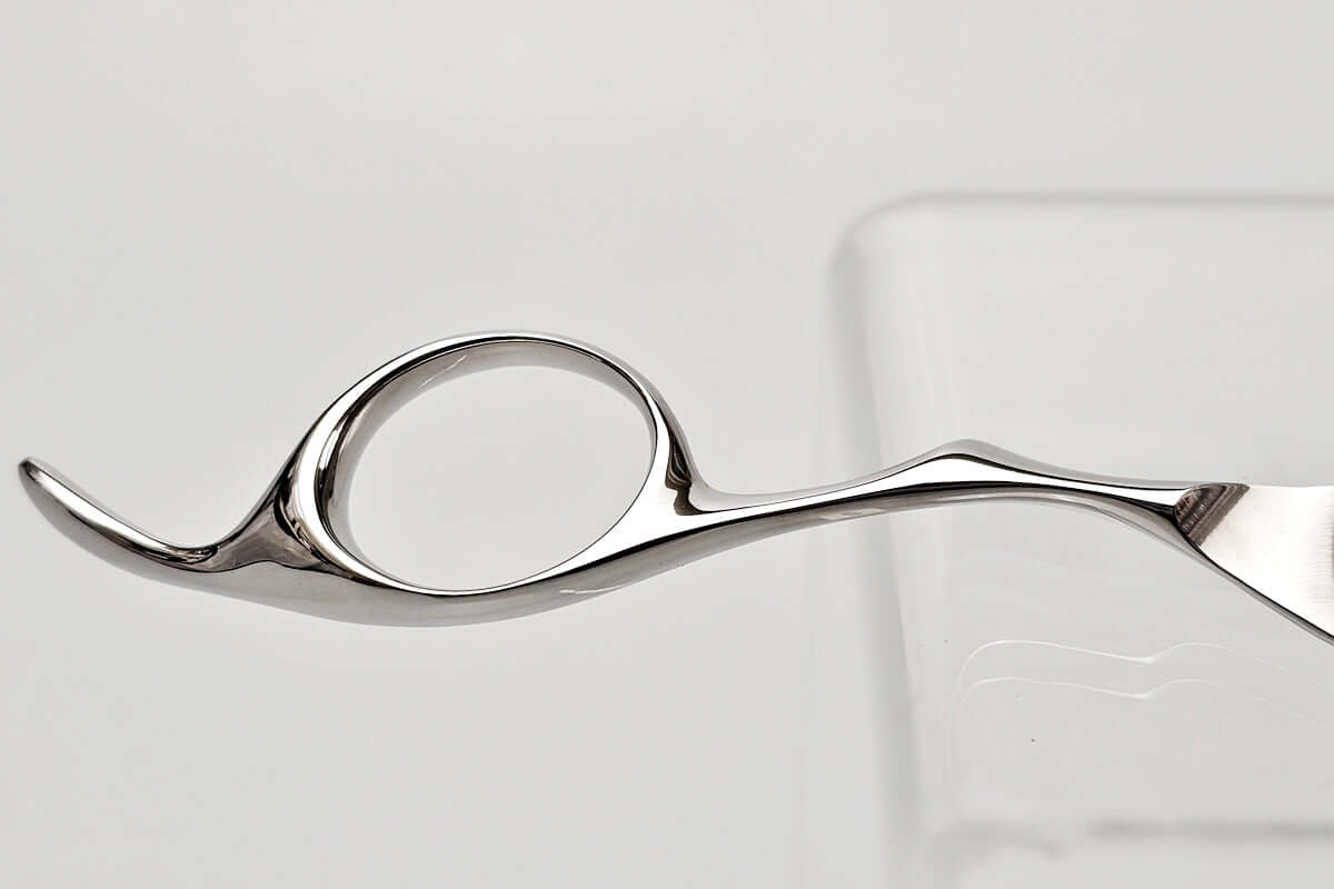 Close-up of a hair scissors finger ring on a light gray background