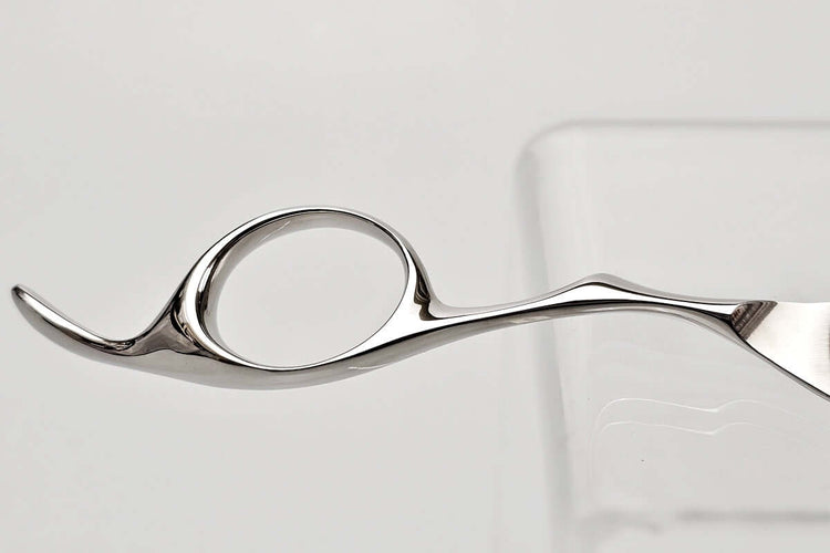 Close-up of a hair scissors finger ring on a light gray background