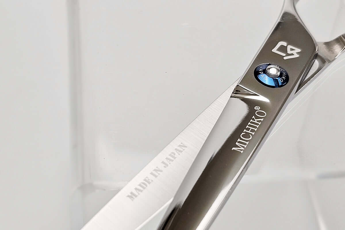 Close-up of a pair of hair scissors with 'Michiko' branding on a light gray background