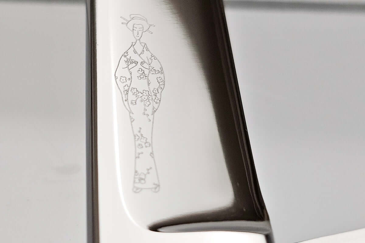 Close-up of hair scissors blade with an engraved MICHIKO lady logo on a reflective surface.