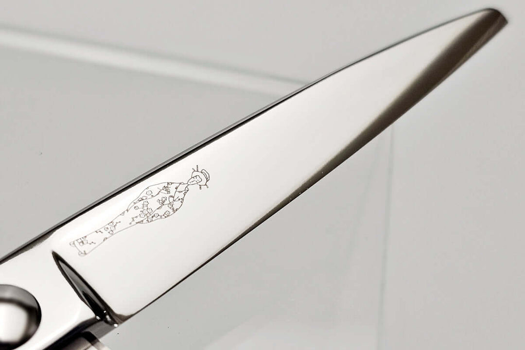 Close-up of hair scissors blade with engraved MICHIKO lady logo on a gray background