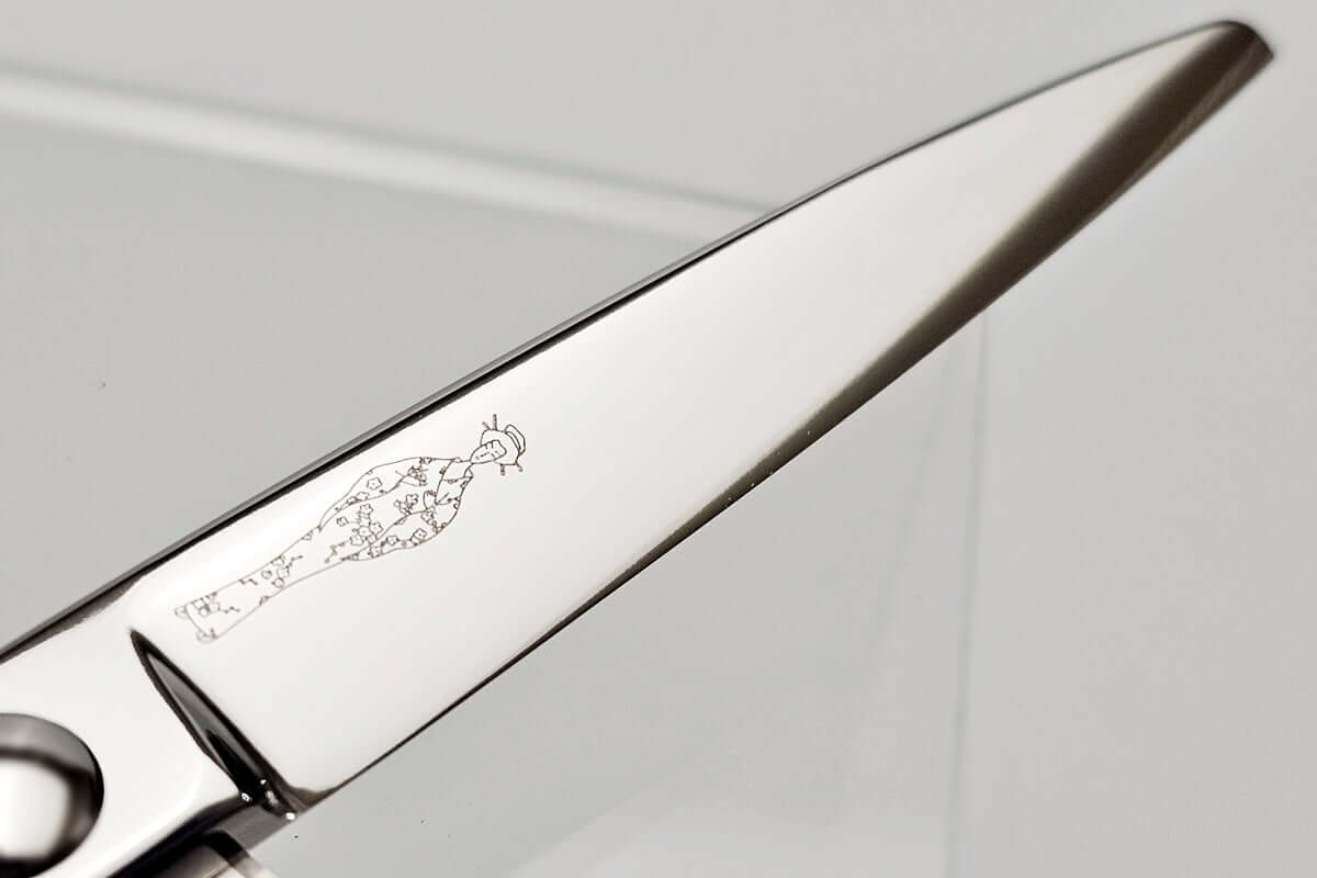 Close-up of hair scissors blade with engraved MICHIKO lady logo on a gray background