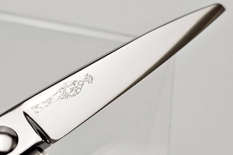 Close-up of hair scissors blade with engraved MICHIKO lady logo on a gray background