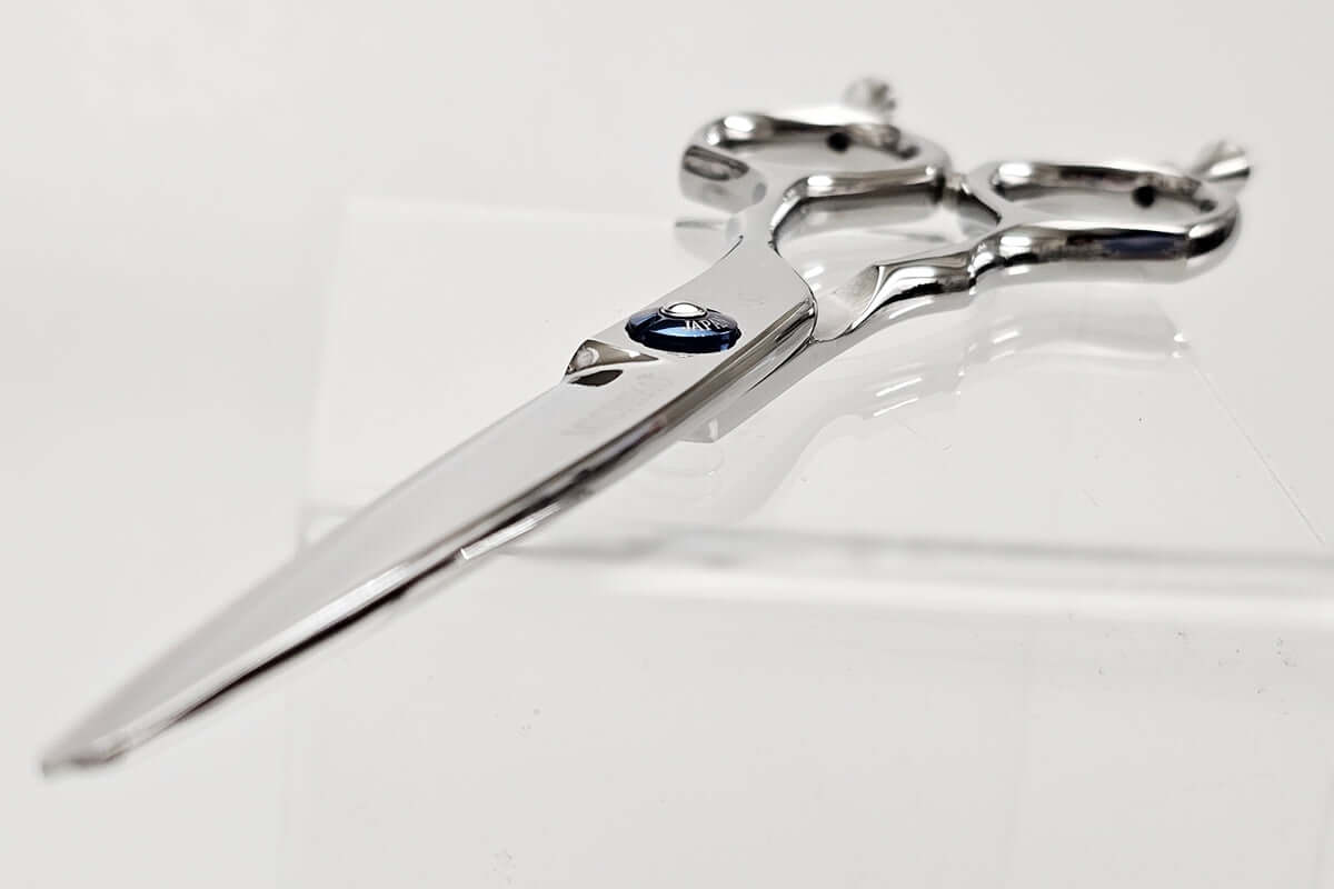 Hair scissors with a blue screw nut on a white background