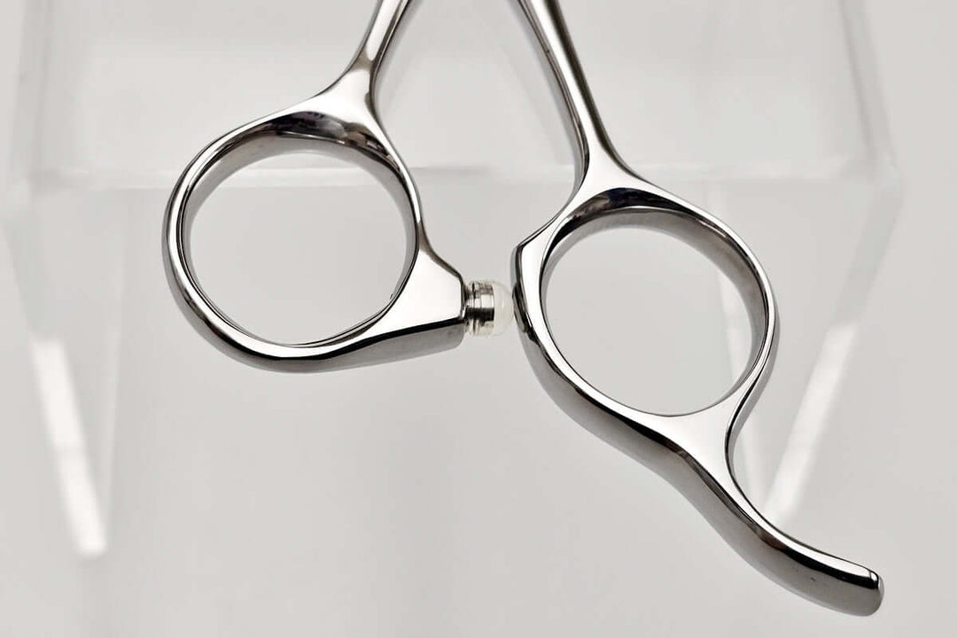 Pair of silver scissors handle on a light gray background